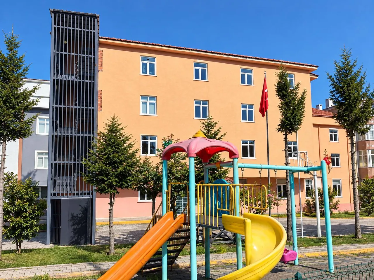Bina önündeki çocuk oyun parkı, kaydıraklar ve salıncak